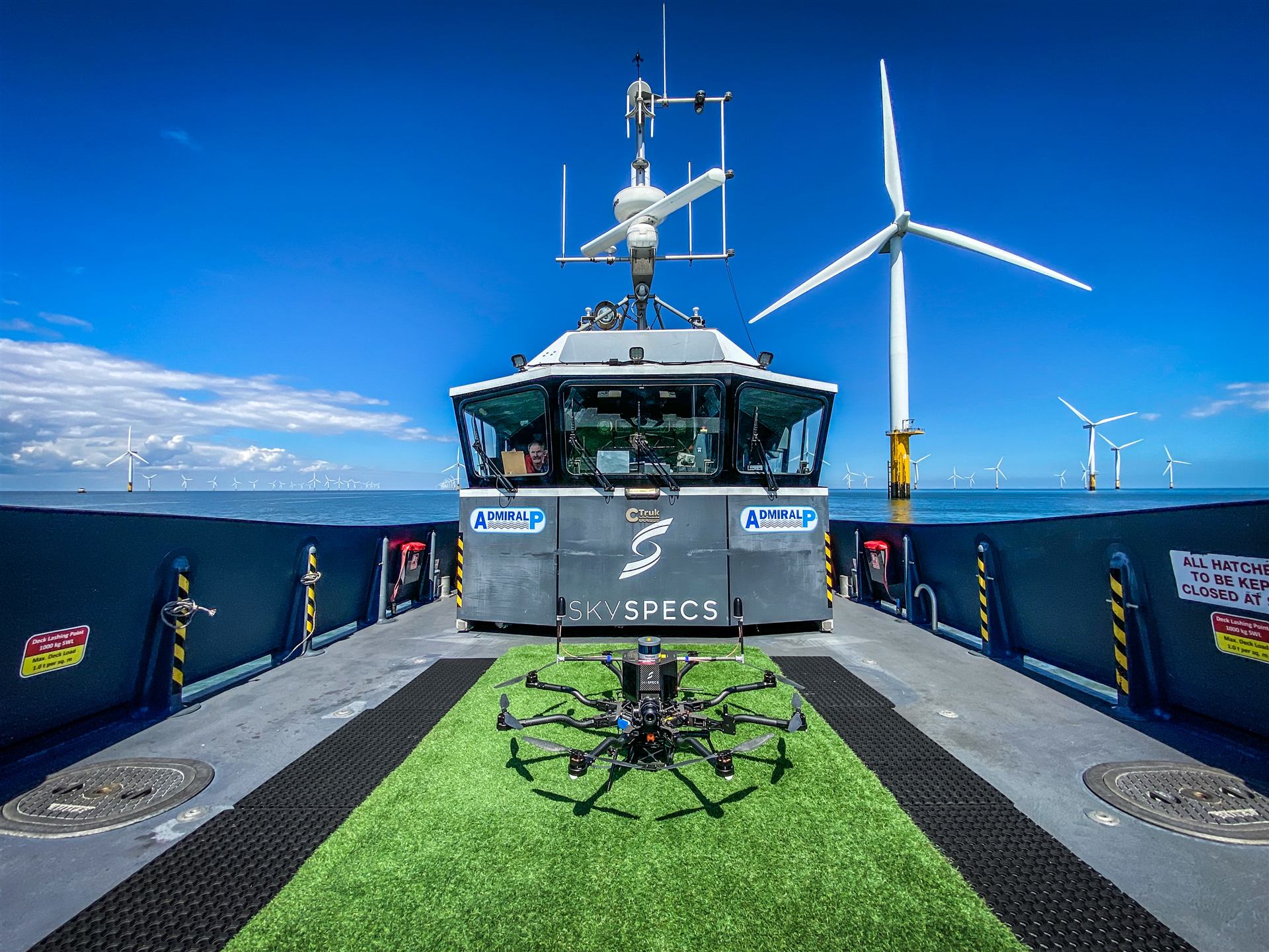 SkySpecs-branded crew transfer vessel with inspection drone on deck at an offshore wind farm